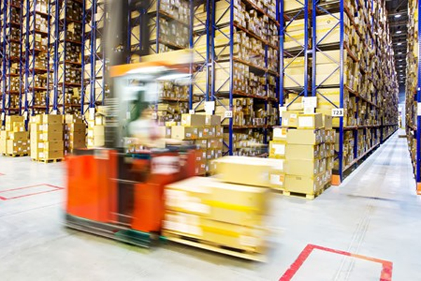 Motion-blurred forklift transporting goods in a well-organized warehouse, representing Impinj's real-time supply chain visibility