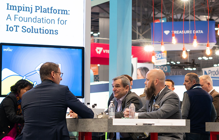 Four people meeting around a table at the Impinj booth at NRF 2024