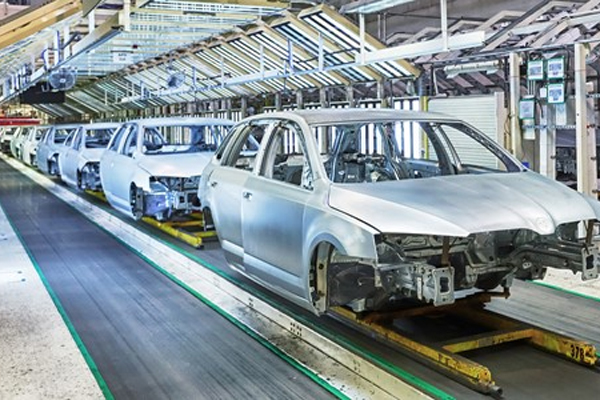 The image showcases a modern automotive assembly line where unfinished car bodies are being transported on