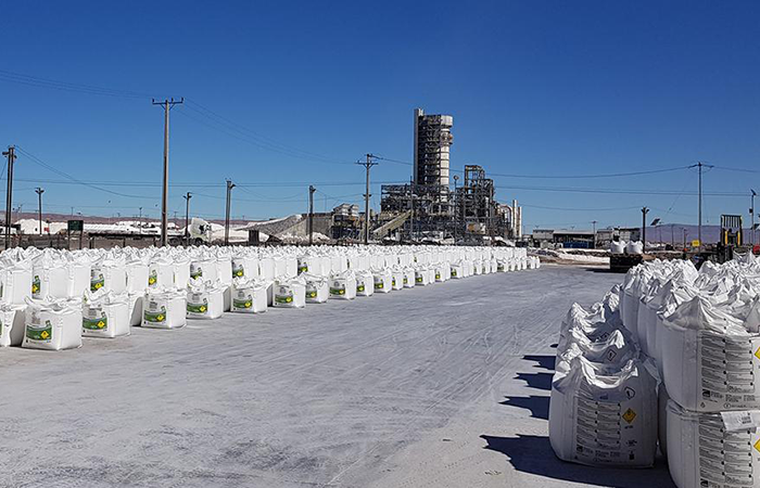 The image displays a vast industrial area under a clear blue sky, showcasing rows of