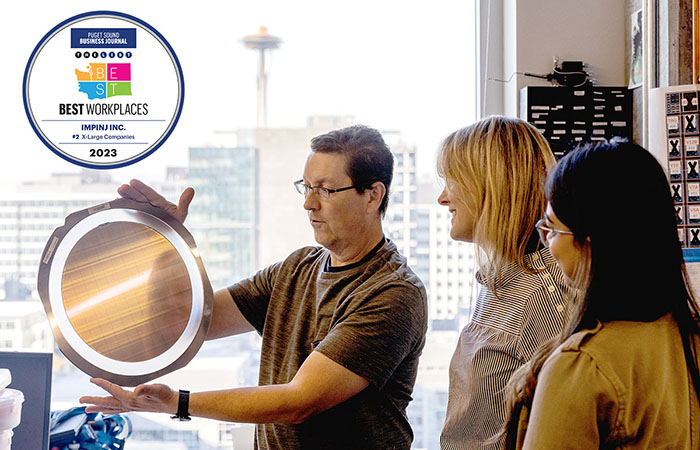 Three colleagues stand together in an office environment, engaging in a collaborative discussion over a