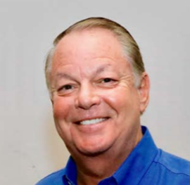 A professional individual wearing a blue shirt stands against a plain background, representing the approach