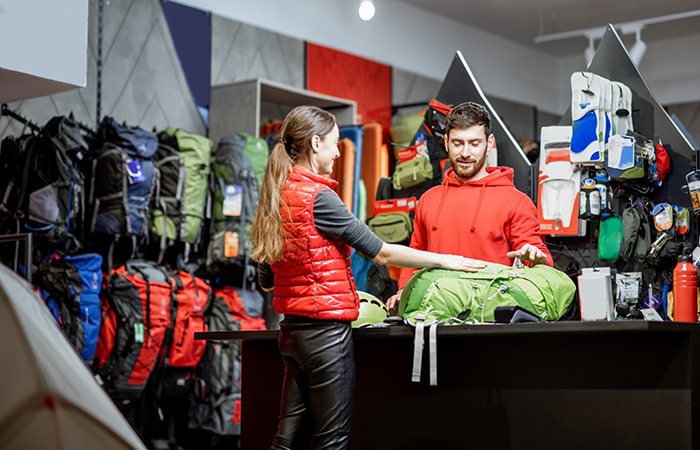 A customer in a red vest is seen interacting with a store employee at a checkout