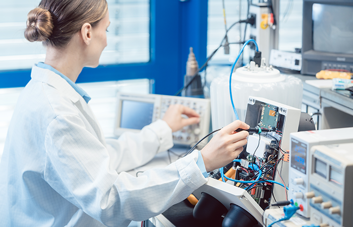 Woman technician calibrating electronic device in tech company laboratory - representing Impinj's dedication to innovation and user experience.