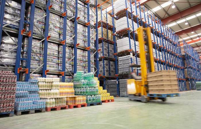 Interior of a well-organized warehouse with high racks full of products and a moving forklift, optimized by Impinj's inventory solutions