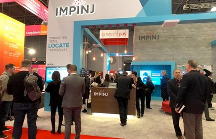 Professionals gather at the Impinj exhibition booth, engaging with interactive displays