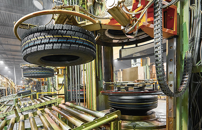 Inside a bustling tire manufacturing plant, stacks of newly minted tires are methodically