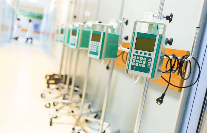 In this image, a row of modern infusion pumps lines the corridor of a brightly