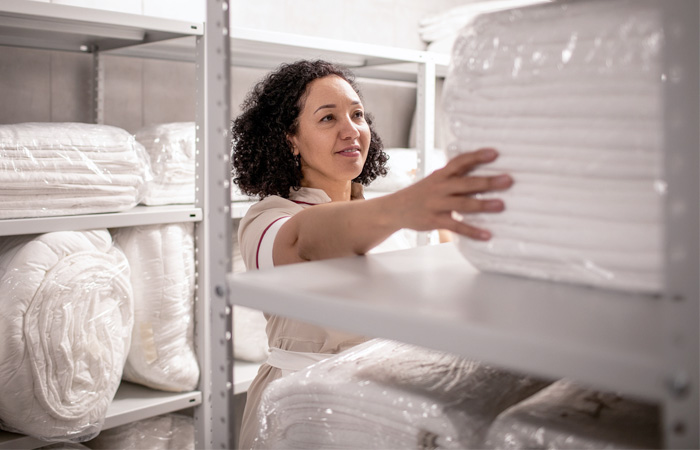 A worker in a warehouse organizes inventory, reaching out to neatly stacked shelves filled