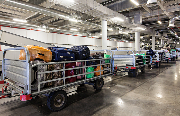 A row of luggage carts loaded with various bags and suitcases is neatly lined up