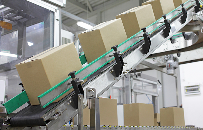 Automated conveyor belt in a warehouse with rows of cardboard boxes, highlighting efficient packaging technology
