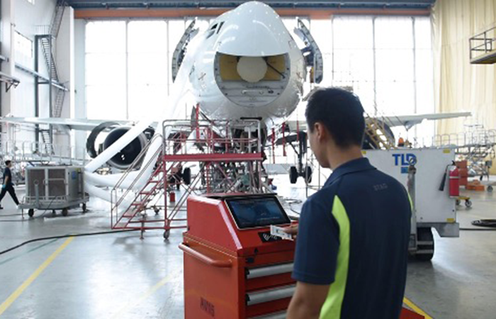 In the bustling environment of an aircraft hangar, a technician attentively operates a
