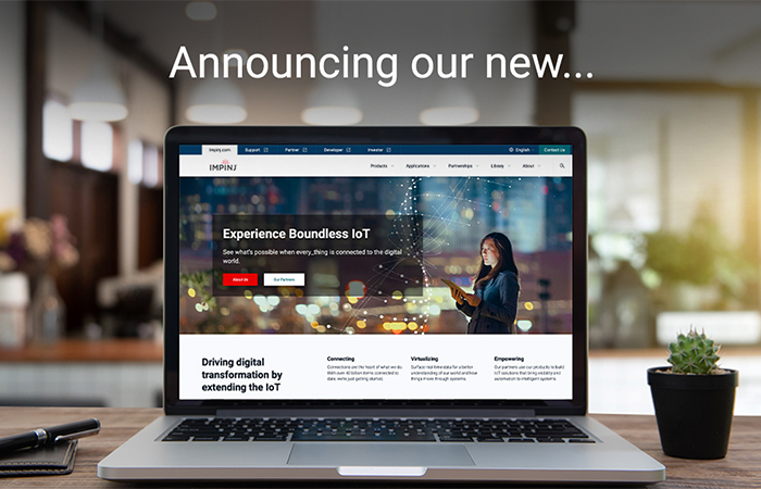 Impinj laptop screen displaying new feature announcement on a desk with a succulent plant, illustrating the enhanced user experience on their IoT-focused website.