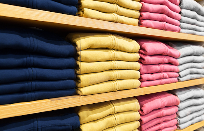 Organized retail clothing display in navy, mustard, pink, and grey, exemplifying Impinj's inventory management solutions