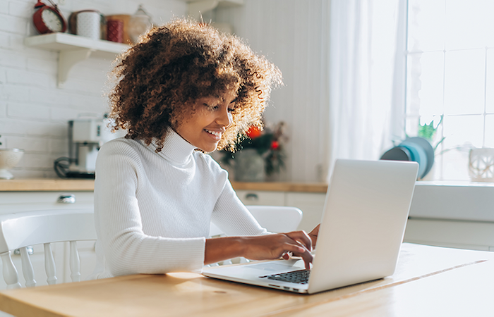 A user is engaged with a laptop at a bright home office setup, reflecting Imp