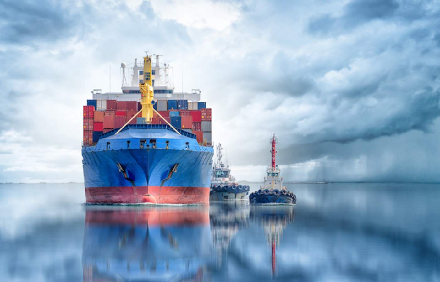 A colossal blue cargo ship, adorned with a vibrant yellow funnel, is anchored at