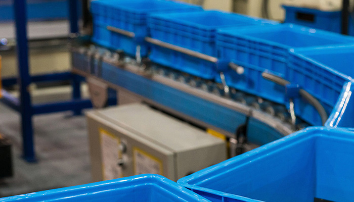 Blaue Kunststoffbehälter auf einem Förderband in einem Lager, das RFID-Technologie von Impinj verwendet