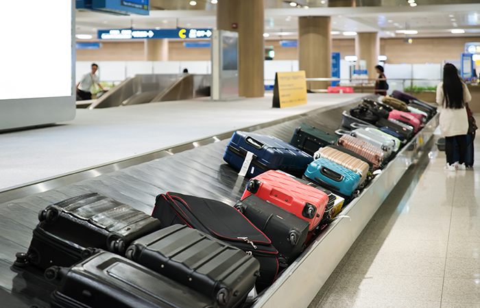 This image captures a busy airport luggage conveyor belt with a variety of suitcases making