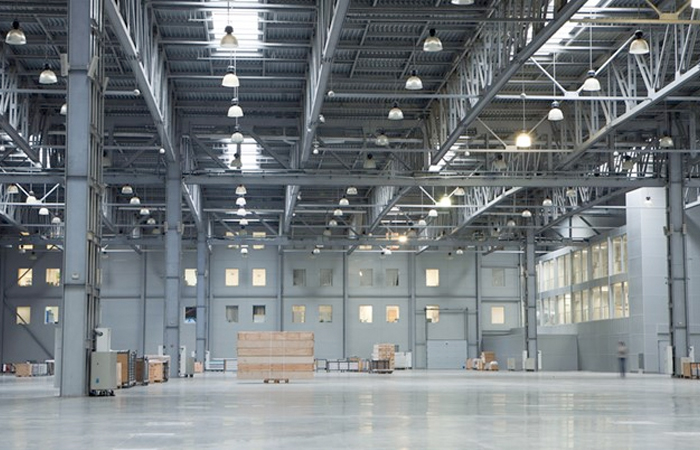The image showcases a spacious and modern industrial warehouse interior, bathed in natural light