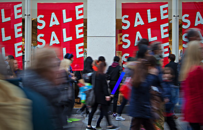 A bustling shopping scene with multiple bright red sale signs in a store's window,