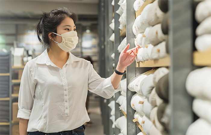 A female employee in a white blouse is selecting items from a well-organized inventory