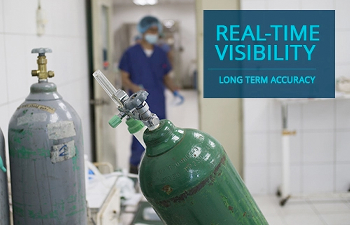 In a clinical setting, a medical professional stands behind a pair of green oxygen tanks