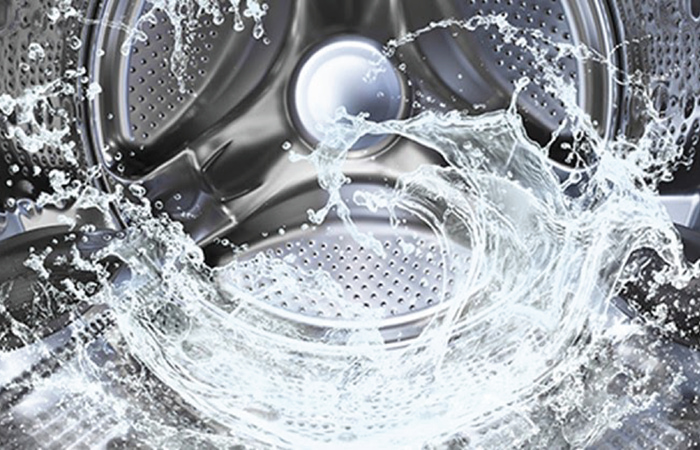 Inside a high-efficiency washing machine, a dynamic swirl of water droplets spl