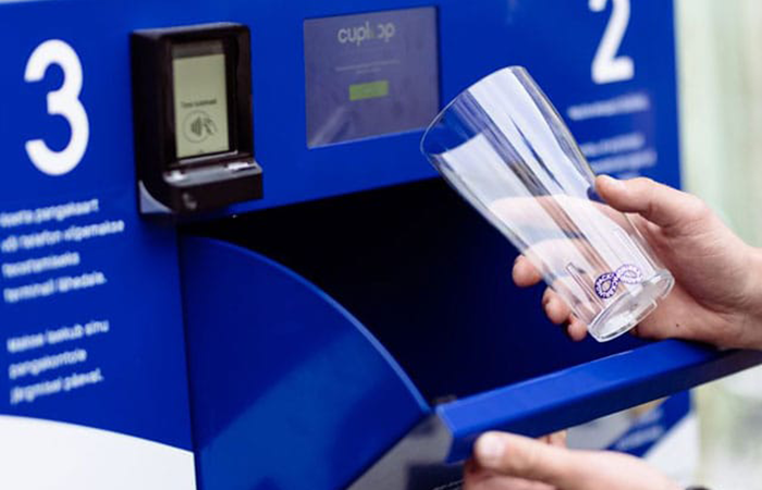 A person is using a modern, interactive kiosk to deposit a recyclable glass