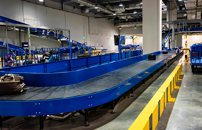 The image showcases a modern, expansive warehouse with a sophisticated blue conveyor belt system designed
