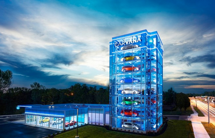 The image showcases the innovative Carvana car vending machine towering against a twilight sky.