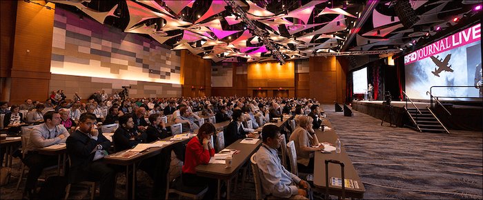 Audience at Impinj RFID conference with '#RFIDJOURNAL LIVE' on screen, embodying interactive user engagement