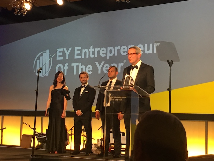 The image captures a prestigious moment at the EY Entrepreneur of the Year awards ceremony