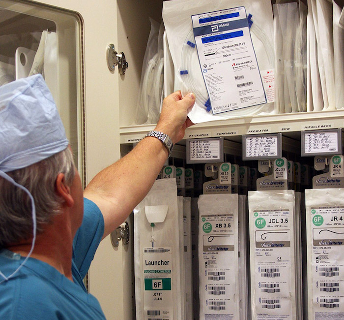 Healthcare worker retrieving a medical item from an organized cabinet, demonstrating efficient inventory management in a clinical setting.