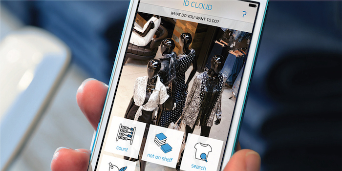 Smartphone displaying ID CLOUD app for inventory management with fashion mannequins in the background