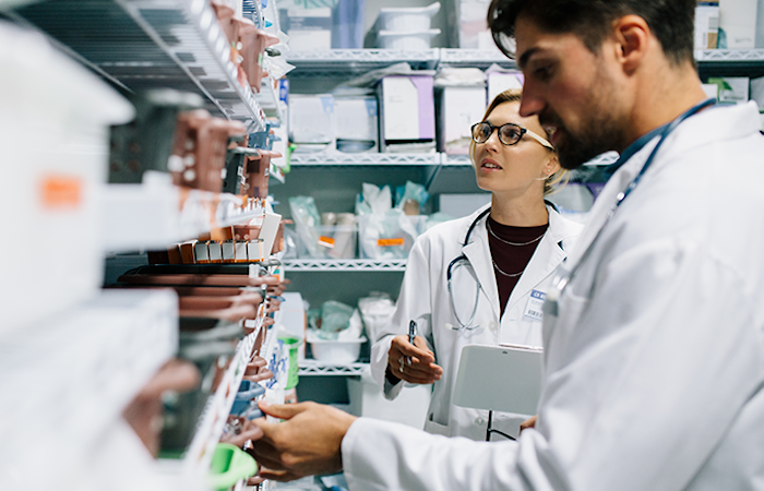 A pharmacist in a white coat is meticulously checking the inventory of medicines on the shelves