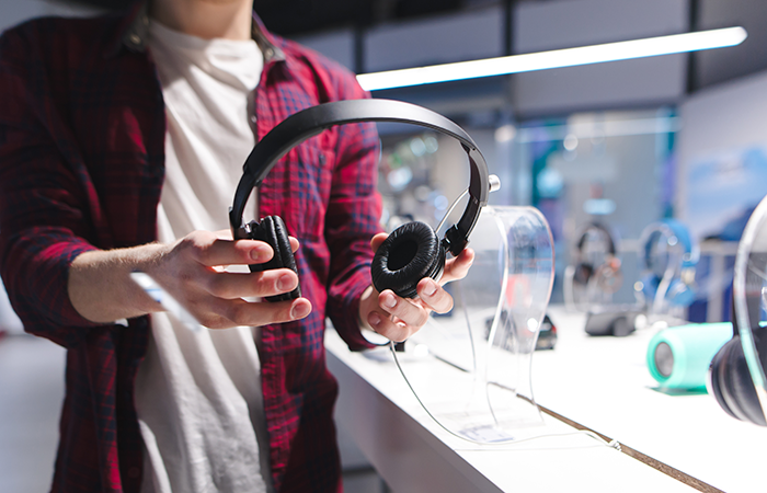A customer is examining a pair of high-quality, black, over-ear headphones