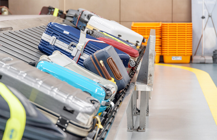 A variety of colorful luggage pieces are systematically organized on a conveyor belt within a modern