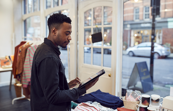 Retail employee using tablet amidst fashionable clothing selection in a bright boutique interior