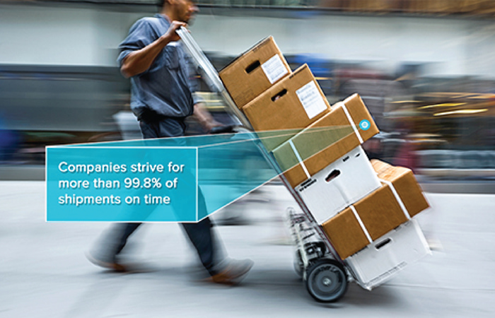 Motion-blurred scene of a logistics worker with a hand truck full of packages, illustrating Impinj's commitment to timely shipment deliveries