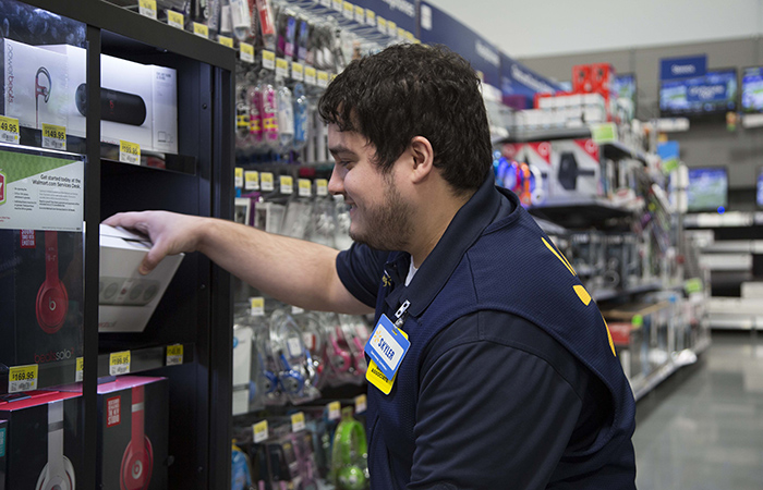 Retail employee restocking shelves with electronic products, showcasing inventory management in a store
