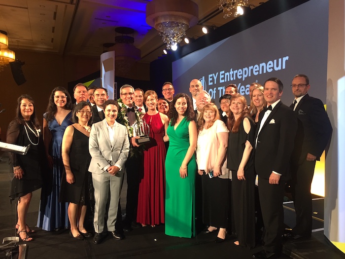 A group of elegantly dressed individuals stands on stage at the EY Entrepreneur Of