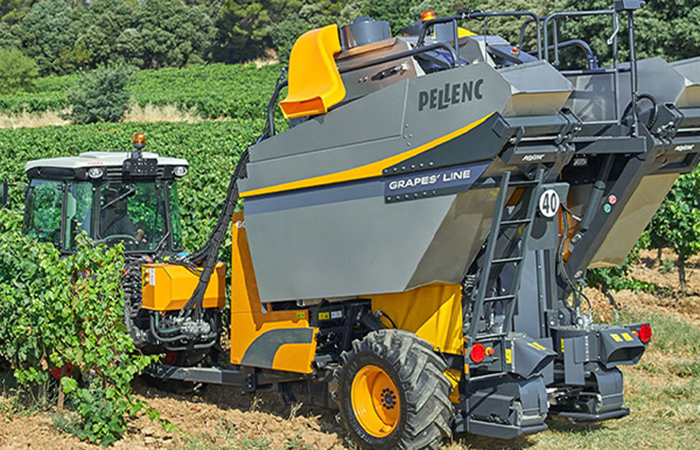 Pellenc grape harvester at work in vineyard, demonstrating Impinj's focus on advanced technology solutions