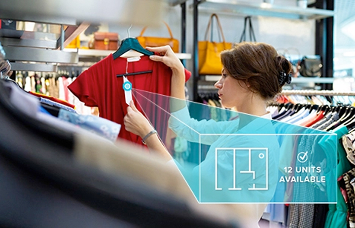 Retail employee checking inventory using RAIN RFID technology indicating 12 units of a red shirt available