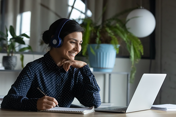 woman-smiling-at-computer-wearing-headphones