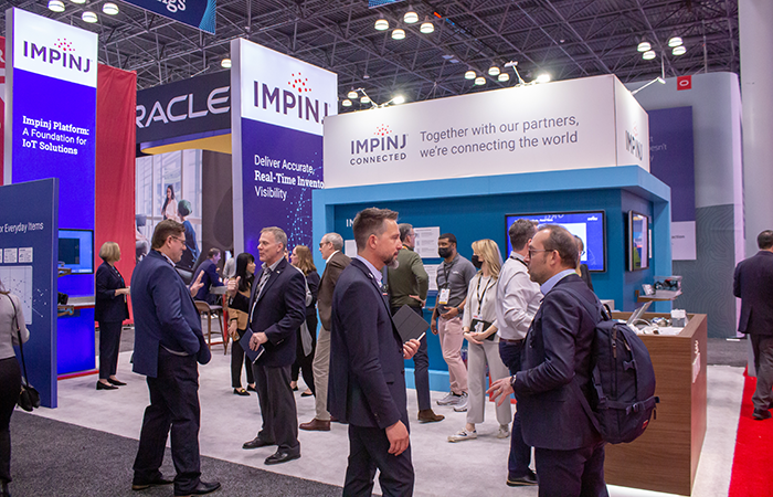 Professionals gather at the Impinj booth, showcasing IoT solutions for real